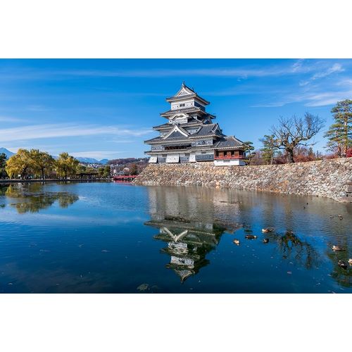 The Matsumoto Castle with reflection in the moat with bridge-walkway and mountains behind-Japan